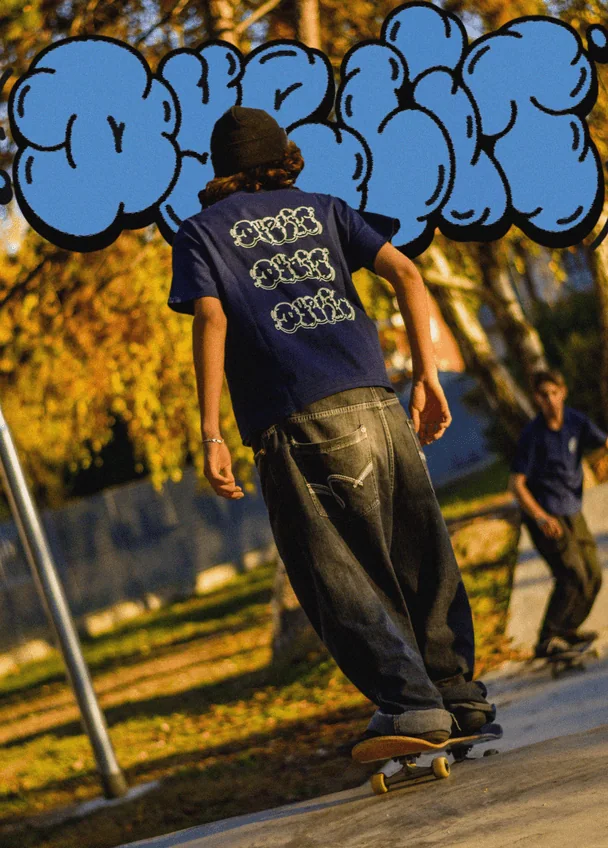 Foto di uno skater di spalle con la t-shirt Dyelit, e sopra un graffito azzurro.