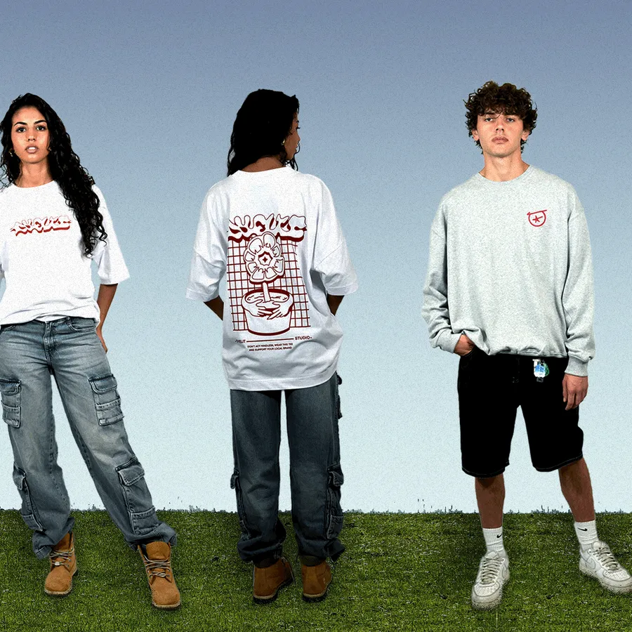 Tre modelli con t-shirt e felpe Dyelit su un prato.